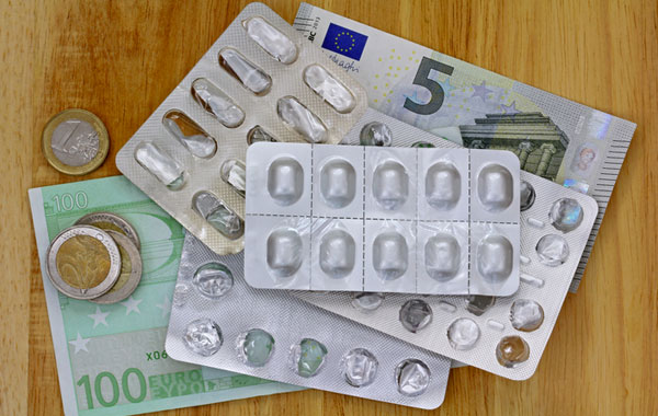 Image of medication pills on top of euro notes and coins
